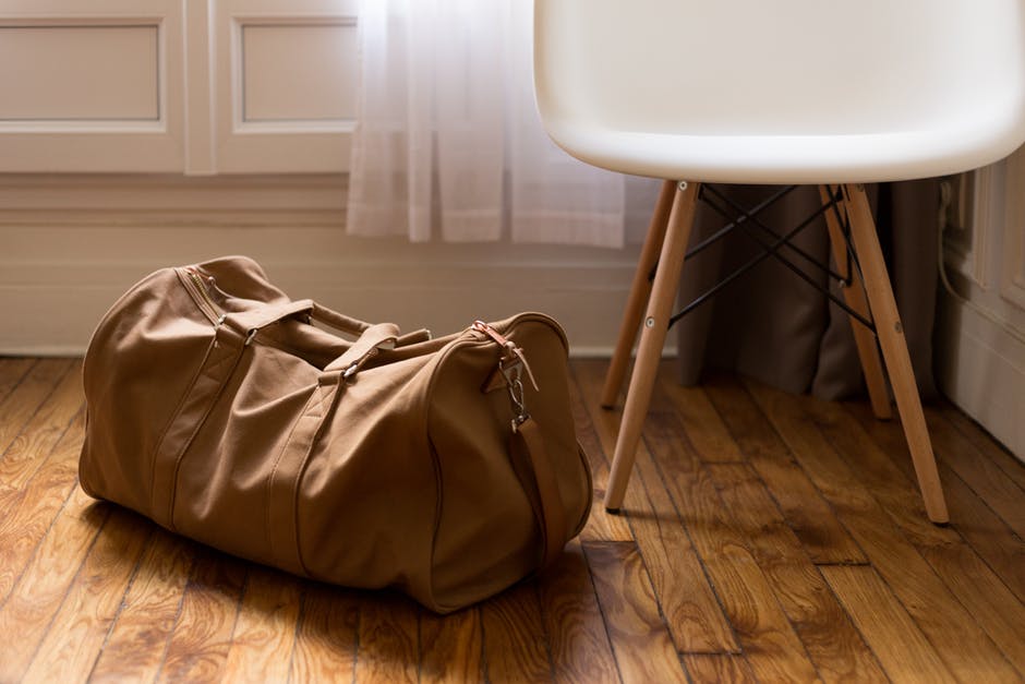 Brown duffel bag next to white chair