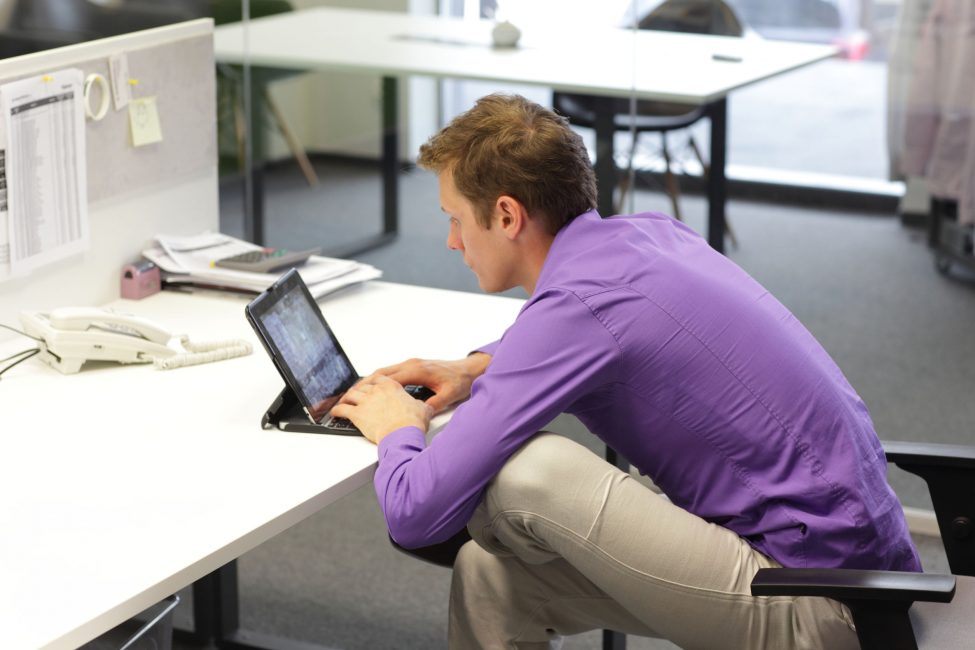 businessman working on a tablet with bad posture