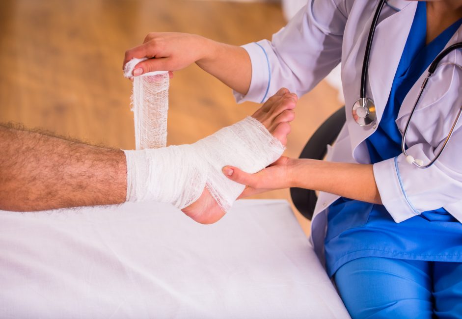 man getting ankle wrapped by doctor