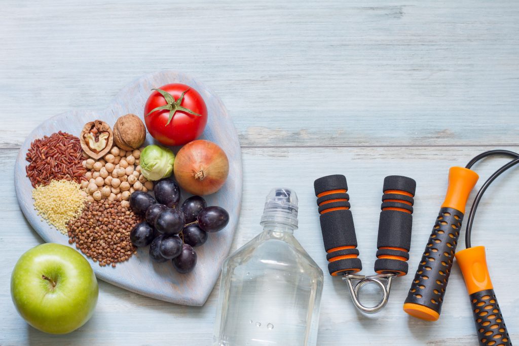 plate of fruits and grains next to a bottled water and jump rope