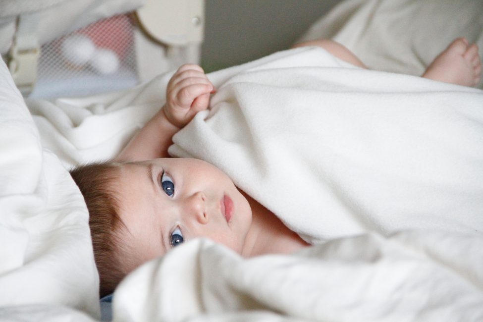 young baby in white blankets