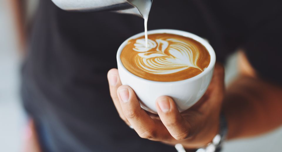 Milk being poured in a coffee cup containing caffeine