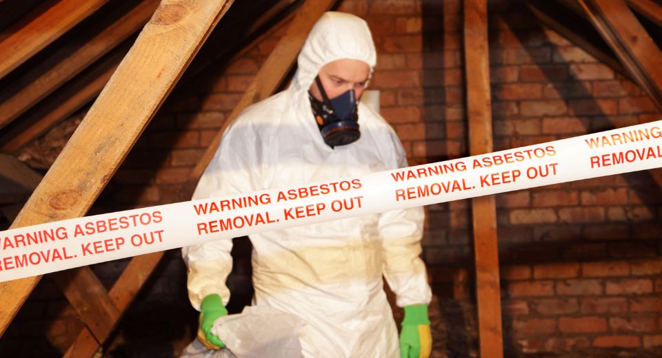 Man in PPE is disposing of asbestos exposure in a home.
