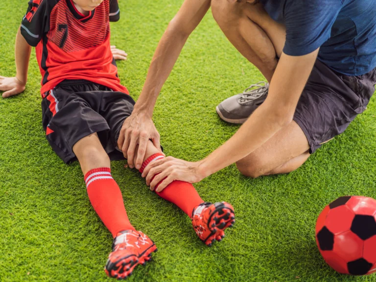 A young kid hurt in a soccer game and a parent checking his knee